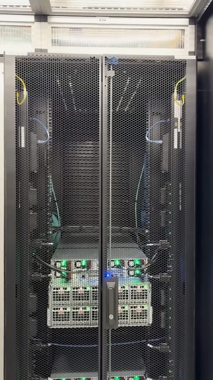 Een gesloten GPU-rack in productie, statusleds groen achter de geperforeerde deuren.